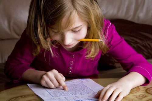 girl with pencil in mouth looking at worksheet